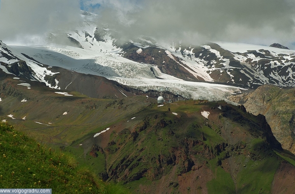 Обсерватория на пике Терскол (3100м). На заднем плане мощный ледник Терскол, спускающийся с Эльбруса. Слева Эльбрус, закрытый облаками. Снято из кресла канатной дороги, поднимающей на г. Чегет.. Кабардино-Балкария, КБР, Приэльбрусье